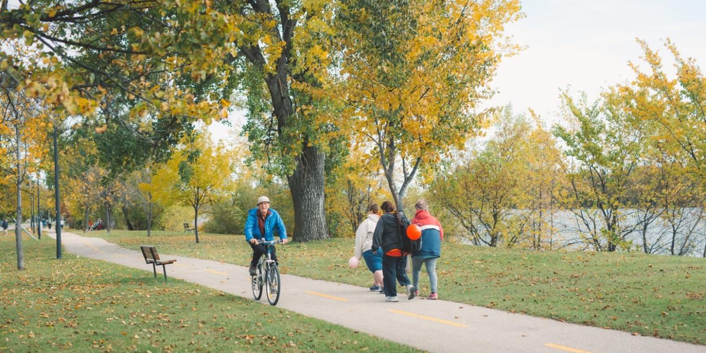 People walking and riding bikes along a path in the park, Portage la Prairie