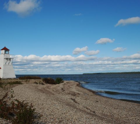 A lone, square, white lighthouse on the point at Hecla.