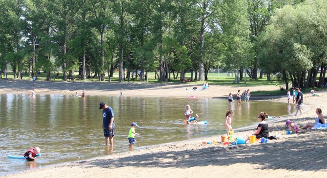 People enjoying the sun and water at the beach in Minnedosa.