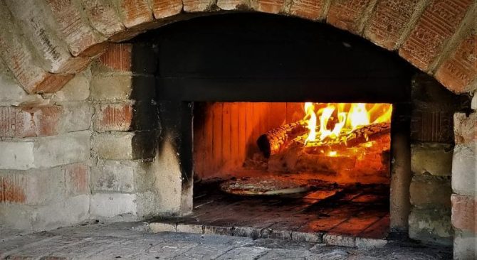 Pizza cooking in a brick wood-fired pizza oven.